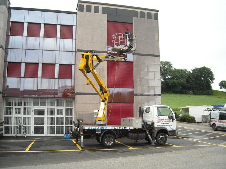 Camion-nacelle en action le long d’une façade vitrée