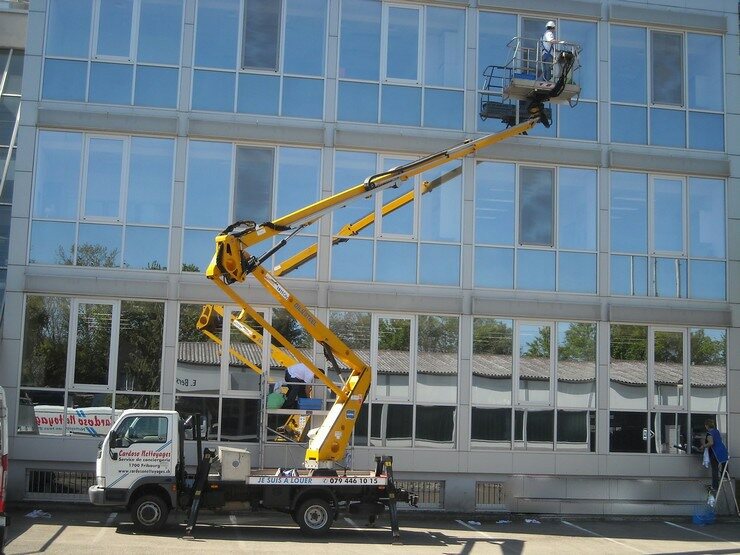 Camion-nacelle Cardoso Nettoyages déployé le long d’une façade vitrée, un collaborateur dans le panier