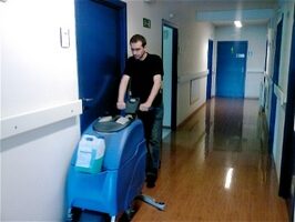 Opérateur conduisant une autolaveuse dans un couloir au sol brillant